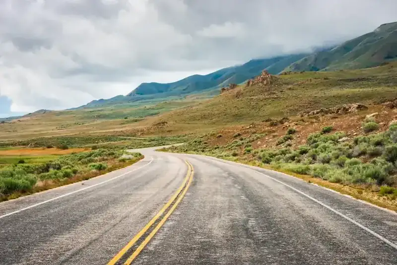A two-lane road curving along the grassy slopes of Antelope Island