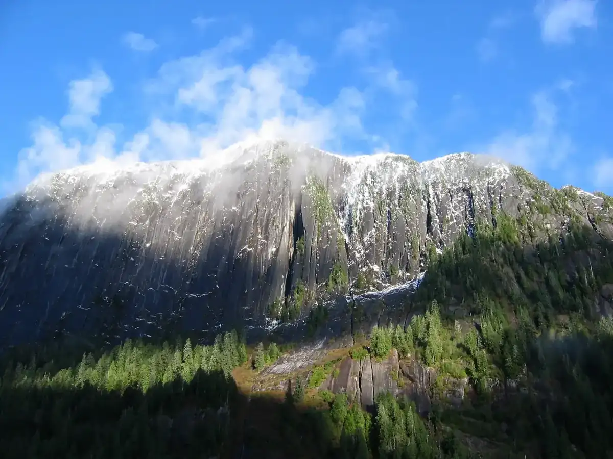 Snow-dusted granite walls rising straight out of the water in Misty Fjords