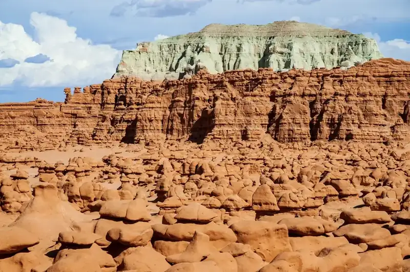 Hoodoos crowded below a green-capped butte at Goblin Valley